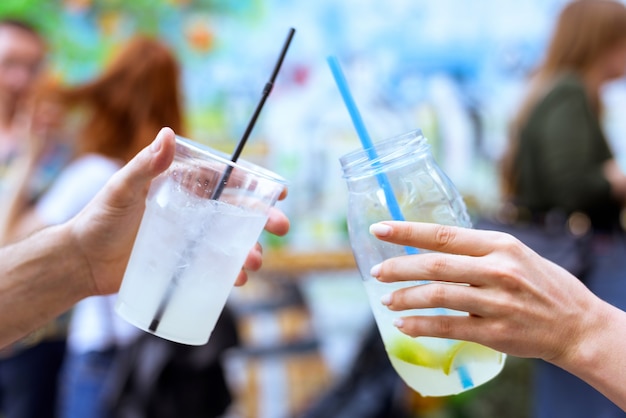 drinking-lemonade-cocktail-glasses-with-straw-and-ice-shaking-man-and-woman-friend-hands-cheers-at-an-event-with-blurred-red-hair-people-and-colored-wall-background_1268-1786.jpg