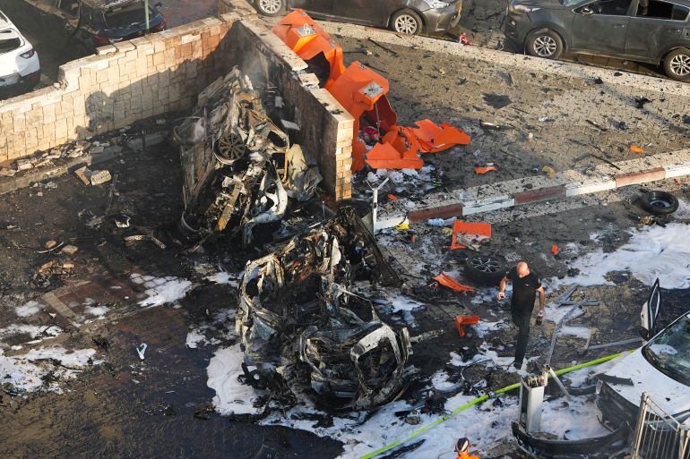 Israeli firefighters extinguish fire after a rocket fired from the Gaza Strip hit a parking lot in Ashkelon, southern Israel