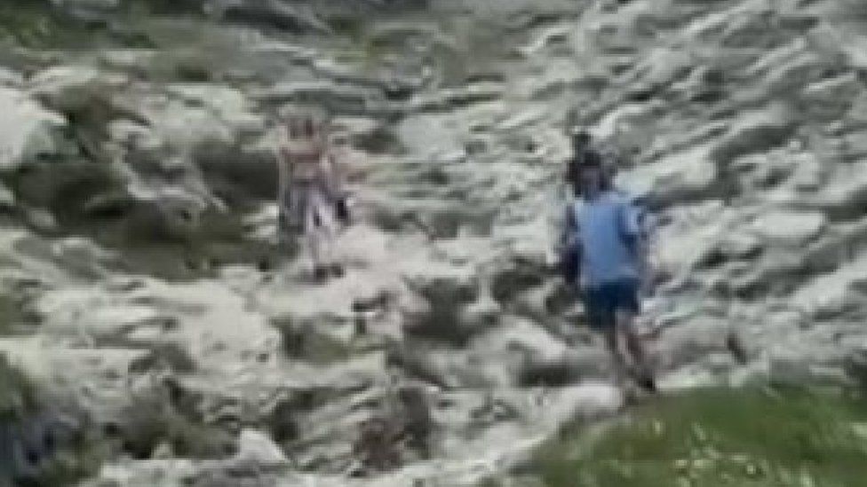 Grainy shot of three people surrounded by rocks