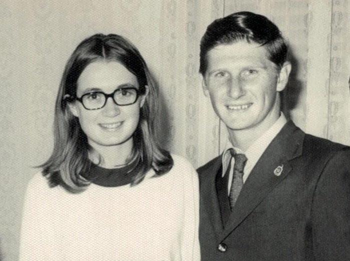 photograph of woman and man smiling at camera, man has hands around her waist