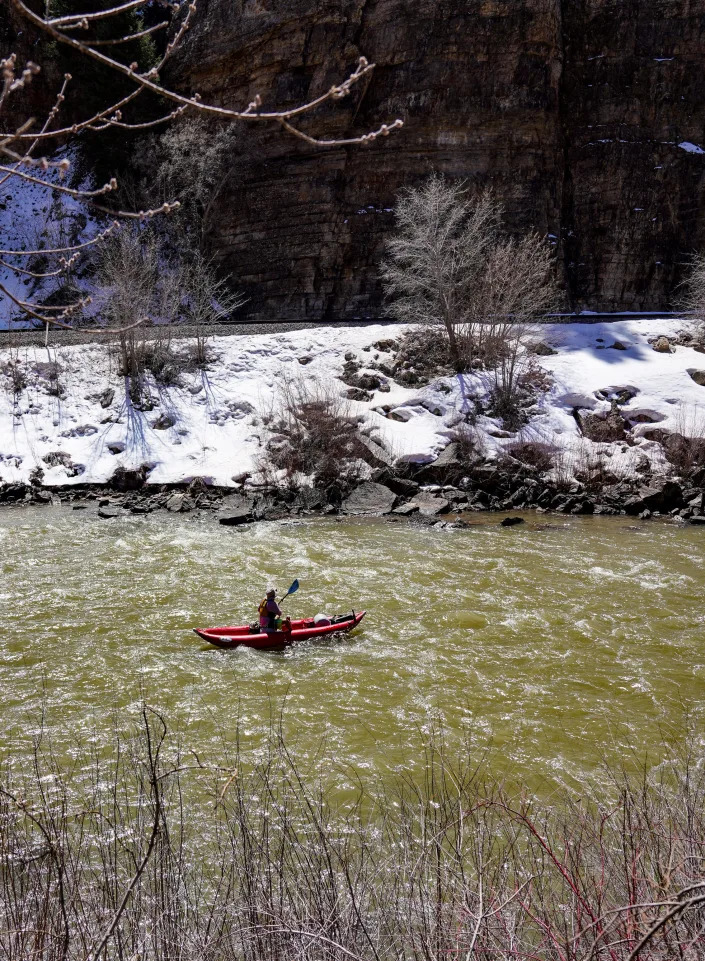 A kayaker floats down the Colorado River through Glenwood Canyon next to Union Pacific railroad tracks.