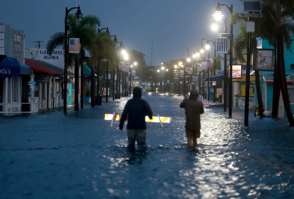Reporters wade through flood waters inundating the downtown area after Hurricane Idalia passed offshore on August 30, 2023, in Tarpon Springs, Florida. / Credit: Getty Images